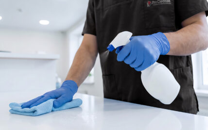 Cleaner disinfecting a reception desk in a GP surgery waiting room